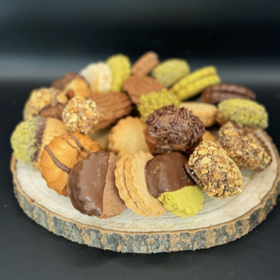A pile of assorted pastries, each with unique flavors and decorations, arranged on a small, round wooden plank with a roug...